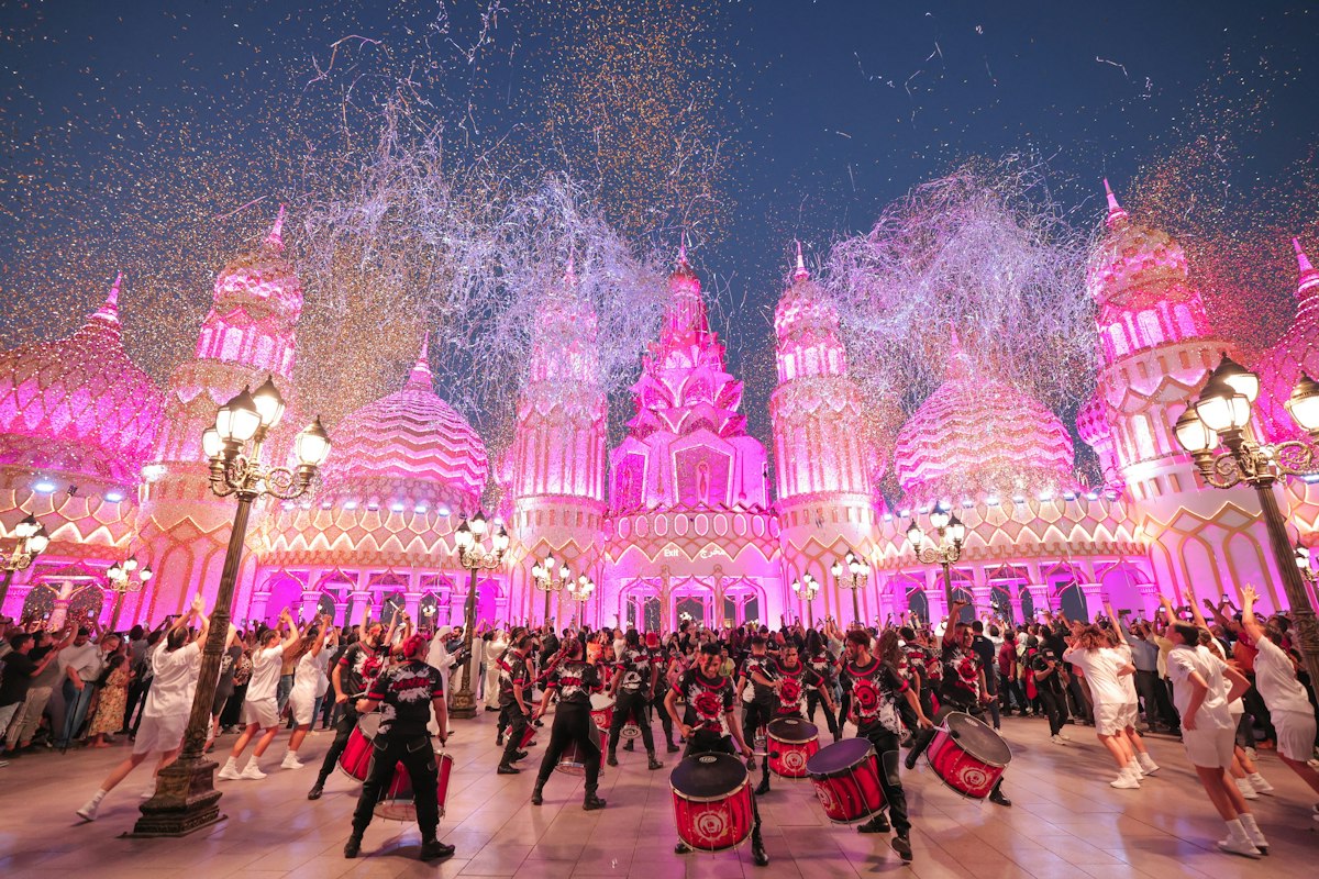 Visitors beneath illuminated Global Village pavilion entrances